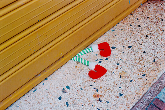 Christmas elf legs stick out from beneath a roller shutter, 35mm film