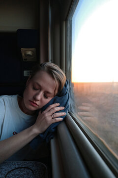 Woman resting on train during sunset journey
