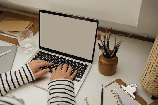 Laptop mockup on white office desk over shoulder view.