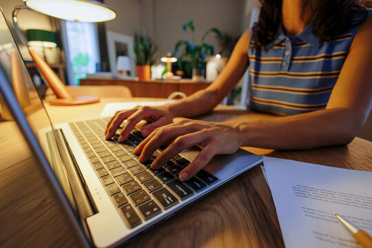 Woman typing on laptop keyboard at home office