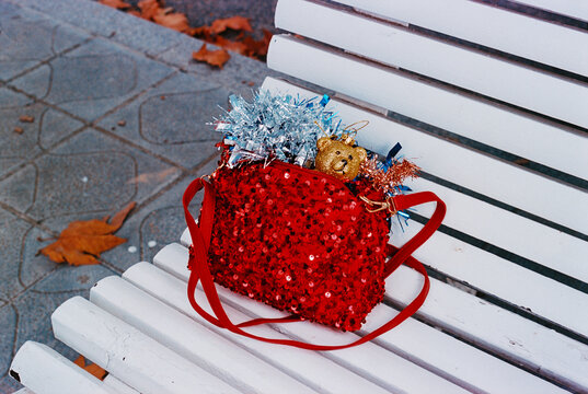 tinsel spills from a red sequined handbag on a street bench, 35mm film
