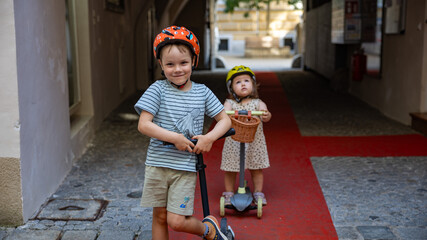 Boy and toddler girl with kick scooters in Graz Austria © Dominik Rueß