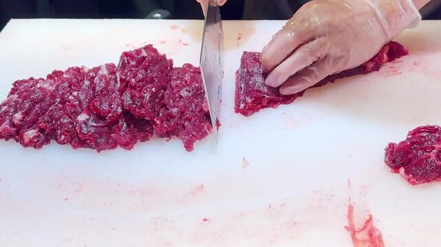 Chef Hands in Gloves Thinly Slicing Premium Beef on White Professional Surface &ndash; Preparing Thin Translucent Meat Layers for Gourmet Dish
