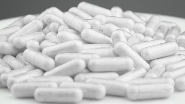Numerous white capsules are arranged in a heap, symbolizing supplements, medication, and wellness. The scene reflects healthcare, pharmaceutical innovation, and daily health routines