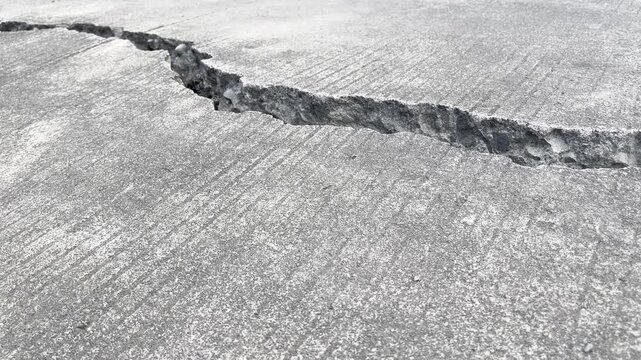 Long deep crack running through concrete road surface