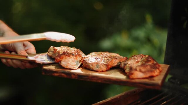 Cooking meat on outdoor grill with tongs during daytime