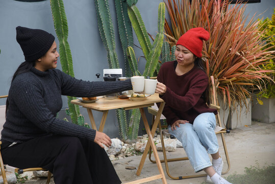 Coffee drip camping friend woman, sitting and talking near cactus garden background, during outdoor winter leisure activity in cozy home backyard for lifestyle concept