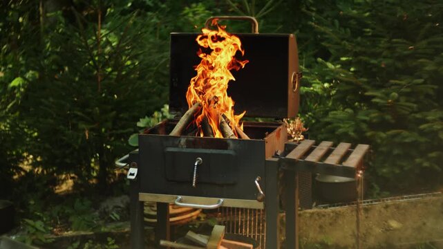 Bright campfire burning brightly inside metal grill outdoors in forest during daytime