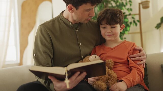 Little boy and his dad read the Bible, learning kindness, faith and values