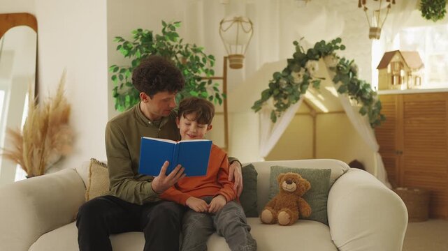 Happy father and his little son read a book together, enjoying family time