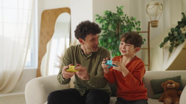 Happy father and little son celebrate video game win with high five and joy