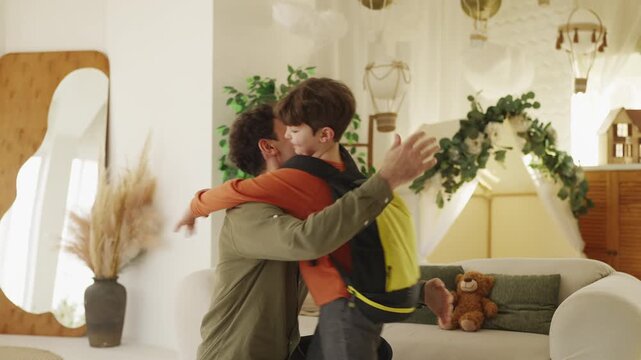 Loving father hugs little son with backpack before leaving home for school