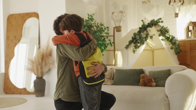 Smiling dad hugs his little son coming back home from school, family reunion