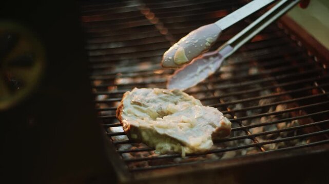 Person grilling food on charcoal barbecue outdoors during evening