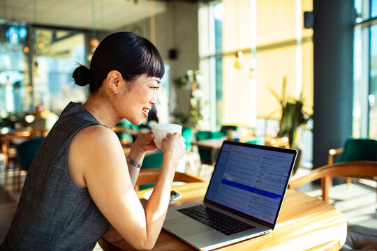 Smiling woman checking email on laptop in cafe