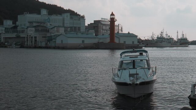 Speedboat Moored at Calm Harbor with Red Lighthouse in Gijang, Busan, South Korea