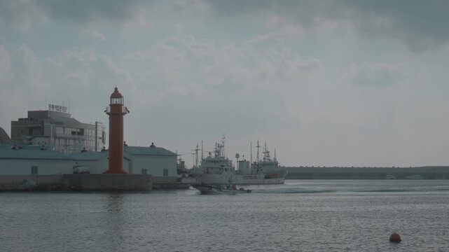 Small Boat Navigating Through Harbor with Red Lighthouse in Gijang, Busan, South Korea