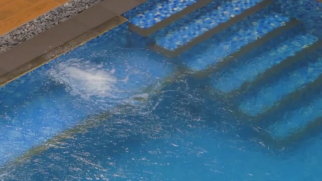 Close up of swimming pool stairs with clear bubbling water