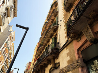 Historic apartment balconies and ornate architecture on a sunny Barcelona, Spain street with wrought iron railings and blue sky © AS Photo Family