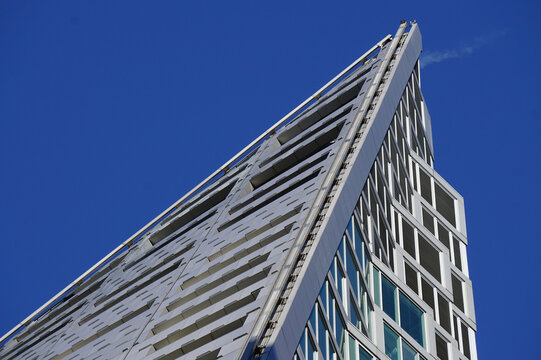 White angular tower prow with stepped balconies against deep blue sky