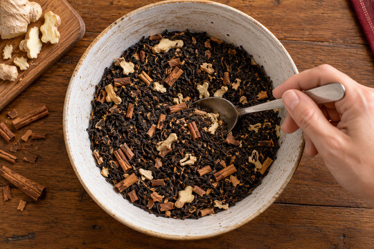 Spicy Chai Blend: A rustic bowl overflows with aromatic loose-leaf black tea, fragrant cinnamon sticks, and fresh ginger pieces, ready to brew a warming cup of chai.