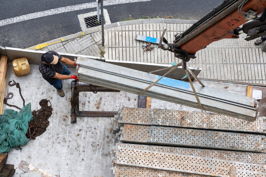 High angle view of a construction worker guiding crane hook loading scaffolding planks onto truck