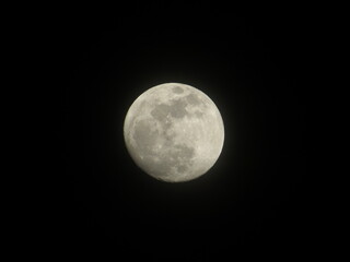 Detailed astronomical macro shot of the bright full moon surface showing craters against isolated black background © VP