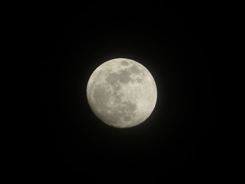 Detailed astronomical macro shot of the bright full moon surface showing craters against isolated black background