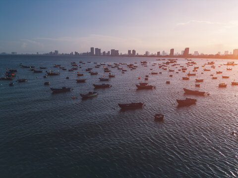 fishing boats anchored in sea bay with Danang city skyline on horizon, high angle coastal seascape view in Vietnam, aerial drone view