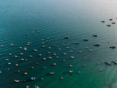 fishing boats anchored in sea bay with Danang city skyline on horizon, high angle coastal seascape view in Vietnam, aerial drone view