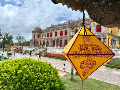 Kien Trung Palace in Hue Imperial City Vietnam, historical landmarks featuring traditional yellow lantern in the foreground with people visiting under a cloudy sky