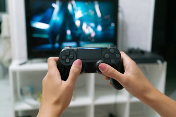 black gaming controller for a console on a woman’s hands © Amickman
