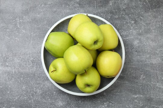Green apples in a plate on grey table