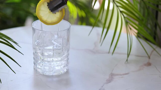 Fresh glass with ice and lemon for refreshing cocktail recipe. Crystal tumbler with citrus fruit slice on white table. Summer refreshment and healthy hydration lifestyle concept