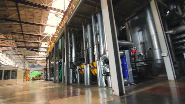 Factory interior pipes pumps. Low angle camera pan industrial plant workshop.