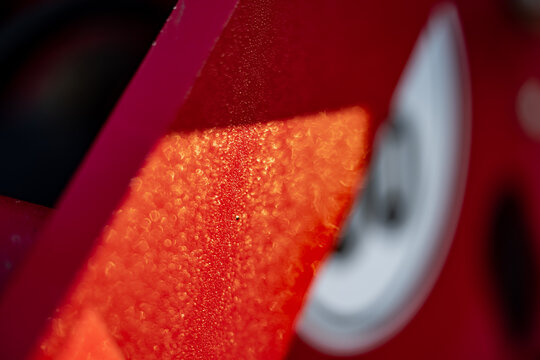Water droplets collect on a painted panel beside an indistinct curved marking, showing moisture on an exposed component relevant to condensation and exterior finish inspection
