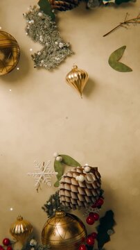 Vertical video: Shifting light causing holiday cluster sparkling on warm craft paper with pinecone