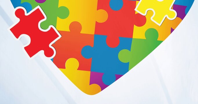 Showing multicolored heart jigsaw puzzle on pale backdrop with detached pieces and paper creases