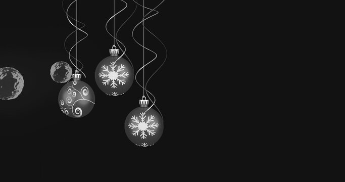 Hanging glossy baubles catching light in studio, with curled ribbons, metal caps, snowflake motifs