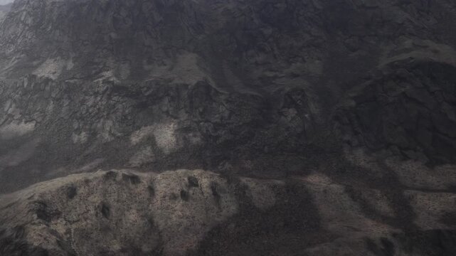 High above, rocky peaks rise majestically under a soft sky. The landscape boasts varying shades of gray and earthy tones, revealing the beauty of natures untouched splendor.