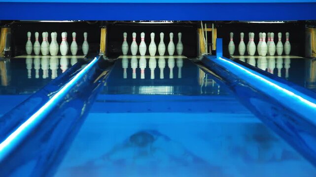 Bowling alley pins neon lights changing color. Empty lanes gutters glow purple.