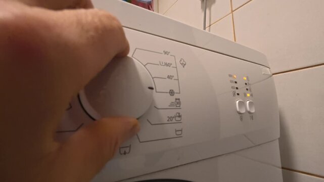 Hand Turning Off Washing Machine with Selector Dial