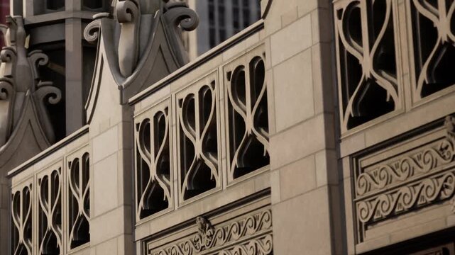 Stone carvings with intricate patterns decorate the exterior of a historic building while a large glass skyscraper rises in the background during the early evening with office lights glowing