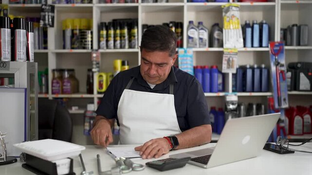 Auto parts store clerk gesturing thumbs up and writing on clipboard behind service counter
