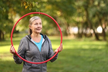 Senior woman with hula hoop in park, space for text © New Africa