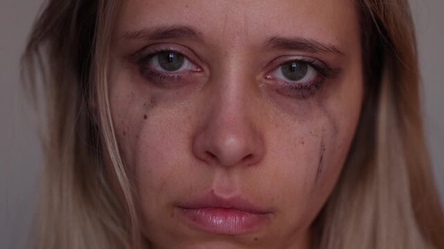 Young blonde woman with an indifferent expression and smeared mascara after crying, looking into the camera and away. Emotional portrait of emptiness, apathy and post-cry exhaustion