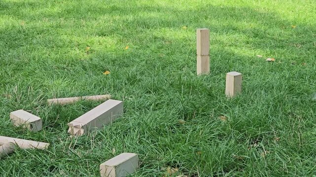The camera glides low over scattered kubb blocks and batons toward the standing pieces. The aftermath of a lively round and the joy of simple outdoor games.