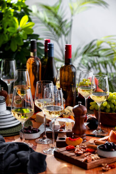 Chilled Friulano white wine bottle set with glasses on wooden table - gourmet food pairing arrangement for friendly lunch. Premium wine tasting setup for restaurant party.