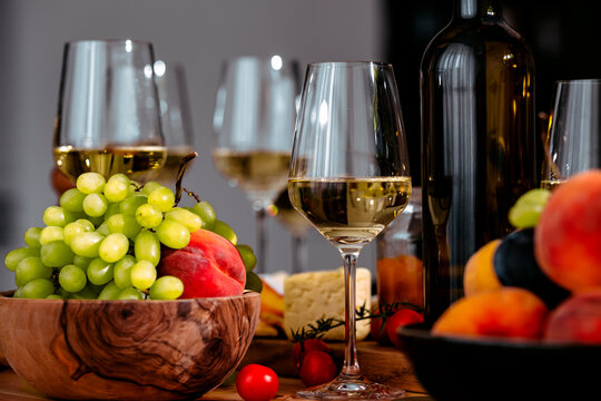 Fresh green grapes with Trebbiano white wine glass and bottle on table - gourmet fruit food pairing concept for wine tasting. Elegant friendly lunch setup for restaurant.
