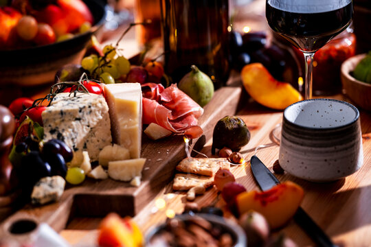 Charcuterie board with blue cheese and prosciutto for wine lunch, autumn food pairing concept. Luxury hospitality dining setting. Gourmet snacks with red wine glass on table setup.